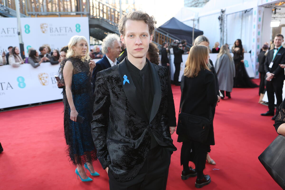 United Kingdom. Actor Felix Krammerer wearing a blue ribbon in solidarity with refugees at the EE BAFTA Film Awards 2023