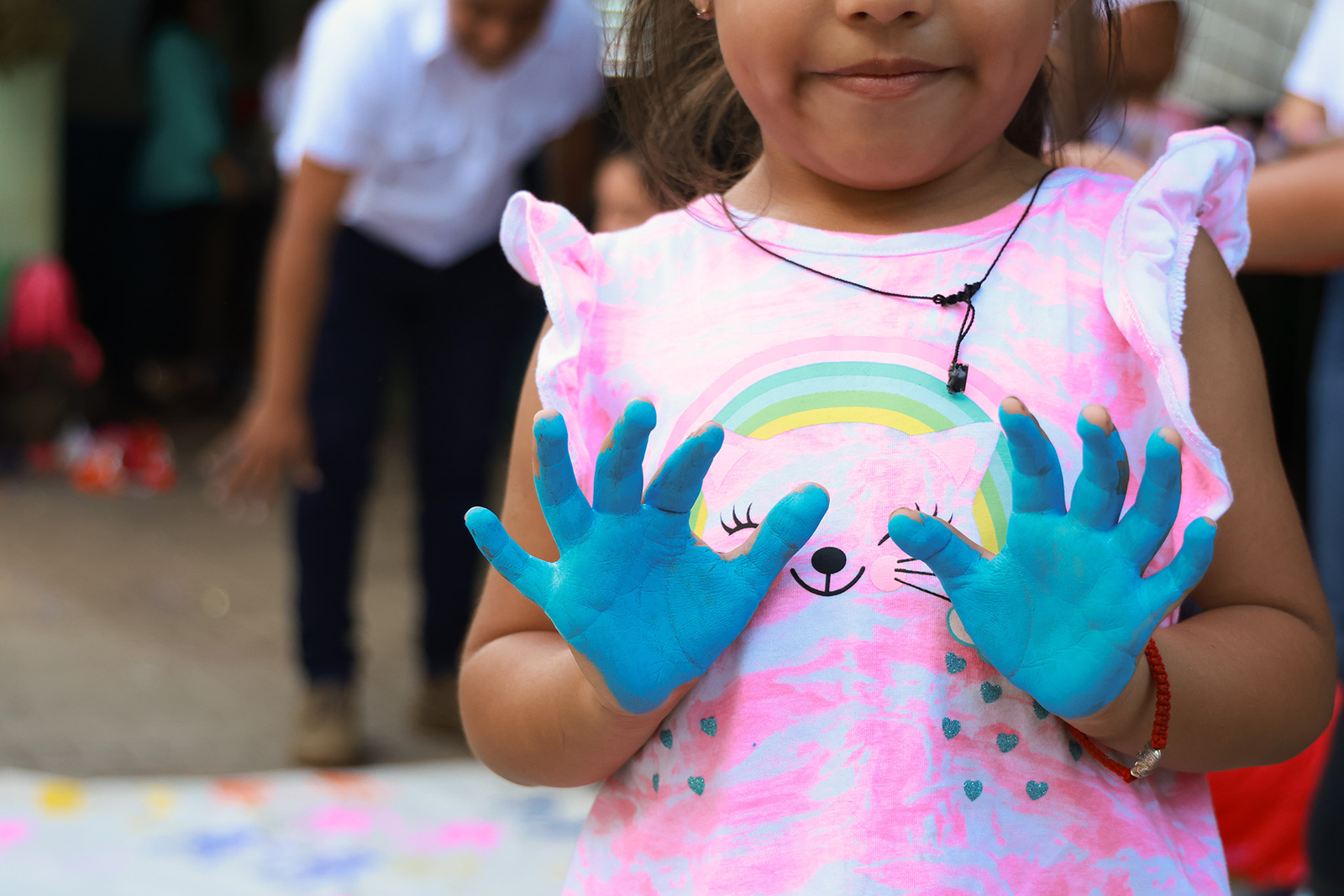 Una niña mustra los palmos de sus manos pintados de azul luego de una actividad lúdica.