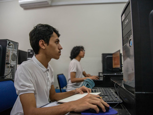 Un joven sentado en un escritorio trabaja con una computadora.