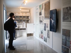 Una persona viendo unos paneles con fotos y una pantalla en una sala.