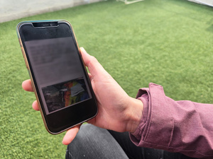 Una mano sostiene un teléfono inteligente donde se ve una noticia difuminada