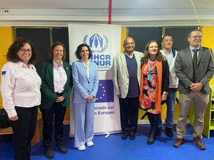 Cuatro mujeres y tres hombres posan para la foto frente a un letrero con el logo de ACNUR y la Unión Europea