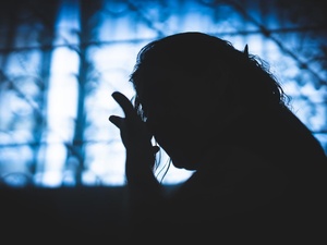 Silueta de una mujer a contraluz en una ventana que refleja luz azul