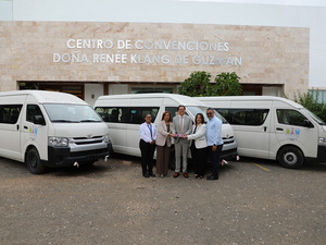 Tre hombres y dos mujeres posan para la foto con tres camionetas blancas al fondo