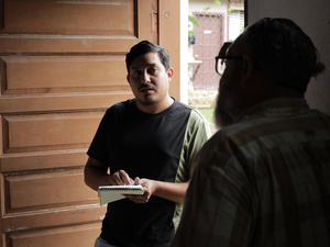 Dos hombres hablando en la entrada de una casa.