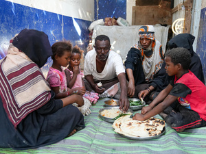 Una familia comparte una comida, sentada en el suelo