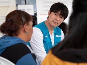 El Embajador de Buena Voluntad de ACNUR Jung Woo-sung habla con personas refugiadas y migrantes en tránsito en el Puinto Wash de Julio Andrade, en Ecuador.
