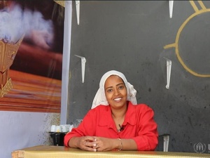 Una mujer con una camisa roja brillante detrás del mostrador de una cafetería.