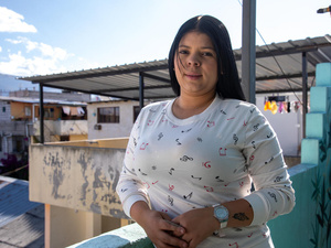 Una mujer posa frente a cámara en un balcón en un día soleado.