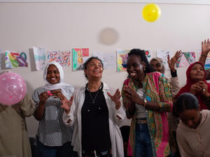 Mujeres aplauden, sonríen y lanzan globos al aire