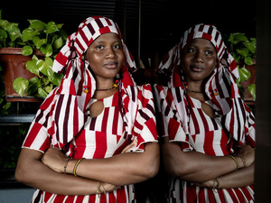 Una mujer de Burkina Faso, que lleva puesto una indumentaria de color blanco y rojo, mira a la cámara con los brazos cruzados sobre su abdomen