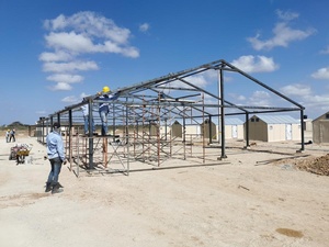 Un trabajador está parado al lado del armazón de un galpón en costrucción.