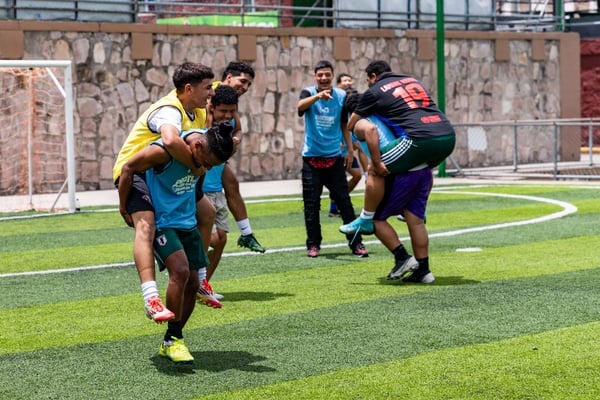 Un grupo de ocho jóvenes varones se divierten en una cancha de fútbol