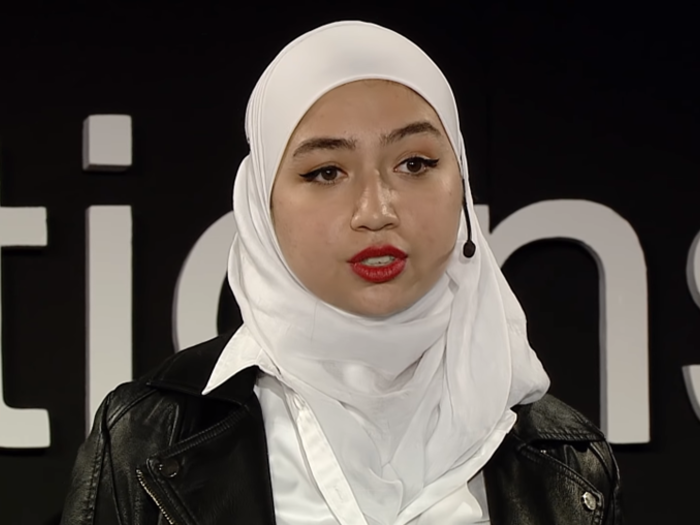 Una joven siria, que lleva puesto un hiyab color blanco, charla con un pequeño micrófono