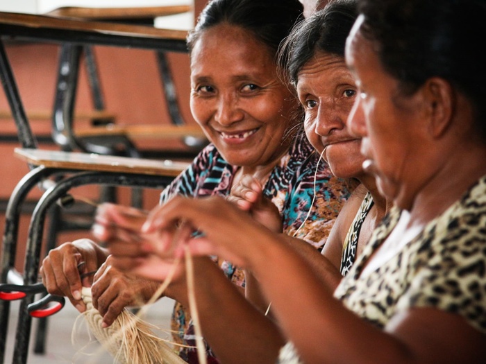 Three old women sit next to each other and craft.