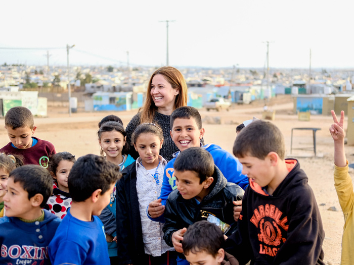 Una mujer y un grupo de niñas y niños sonríe a la cámara
