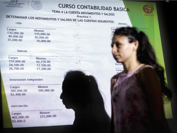 Una mujer frente a una pantalla proyectada que habla sobre un curso de contabilidad