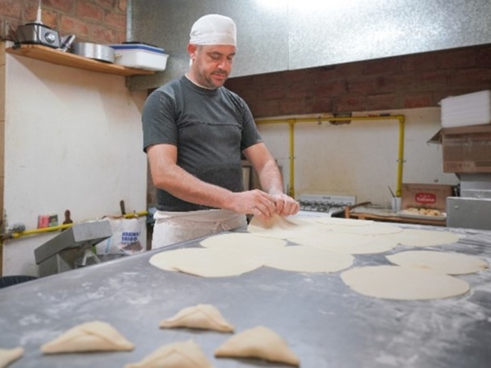 Un hombre está haciendo empanadas frente a una plancha