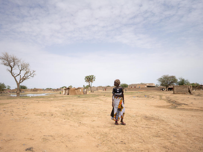 Una mujer camina junto a un gran charco creado por las lluvias recientes en Dori, Burkina Faso.