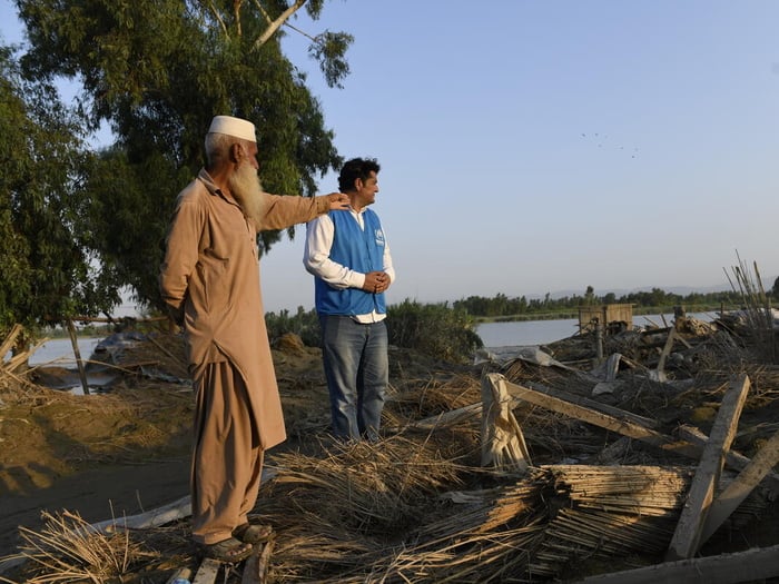 Un refugiado afgano y un trabajador de ACNUR charlan en un espacio afectado por las inundaciones en Pakistán
