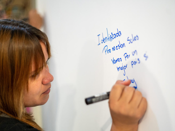 Una mujer escribe sobre un pintarrón blanco