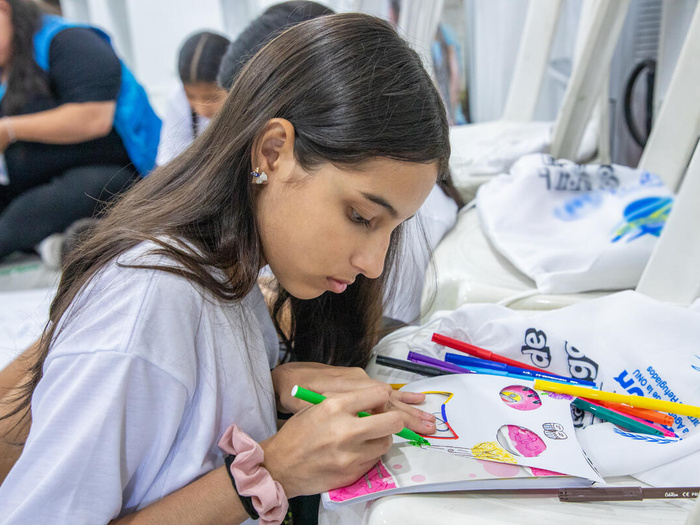 Una chica venezolana dibuja en una hoja con marcadores de distintos colores