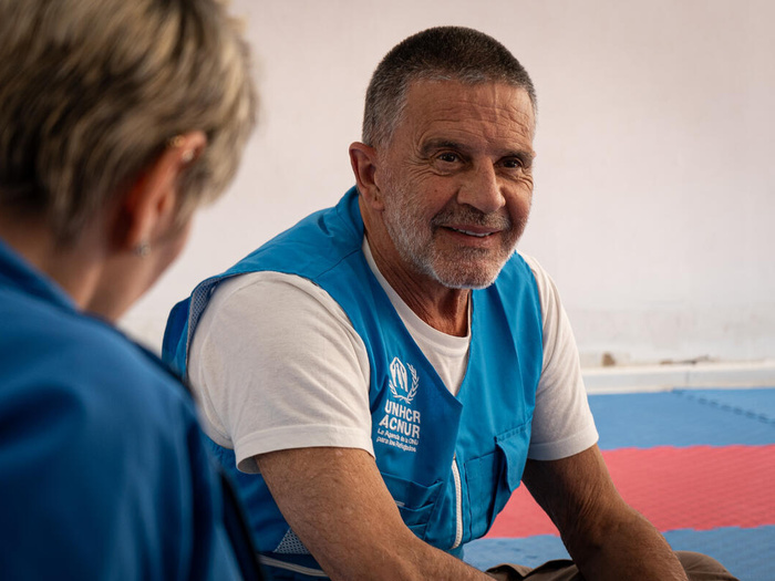 Un hombre sonriente con chaleco azul de ACNUR