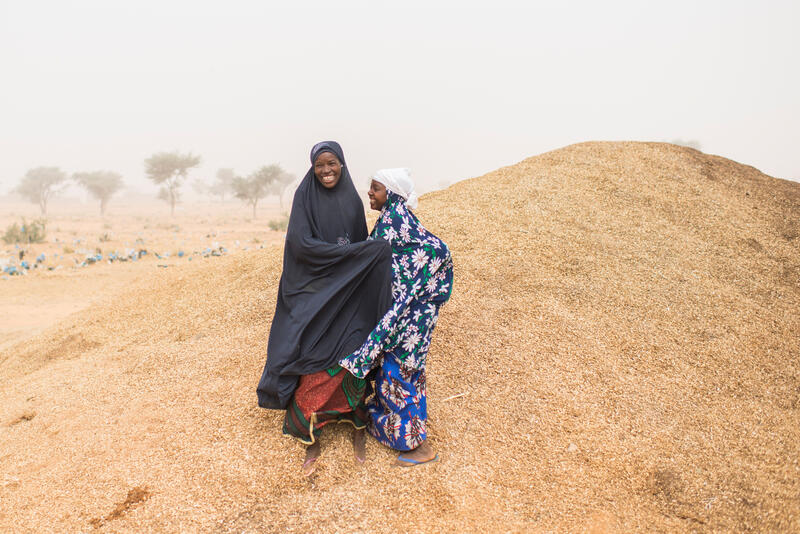 Dos mujeres ríen juntas en una pequeña colina.