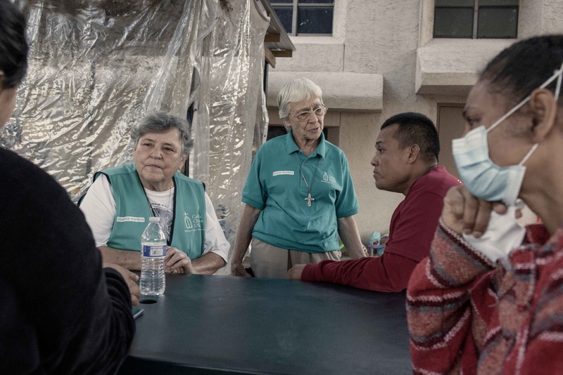 Dos trabajadoras humanitarias alrededor de una mesa hablan con tres personas en necesidad