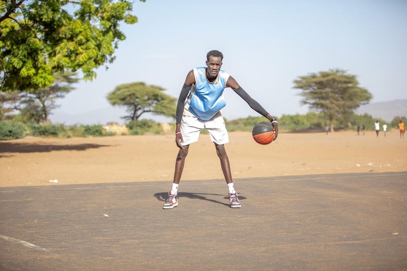 Un hombre de Sudán del Sur rebota un balón de básquetbol en un campamento de refugiados