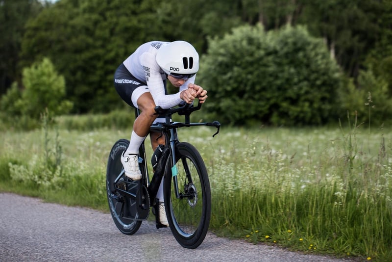 Un hombre vestido de blanco sobre una bicicleta profesional negra
