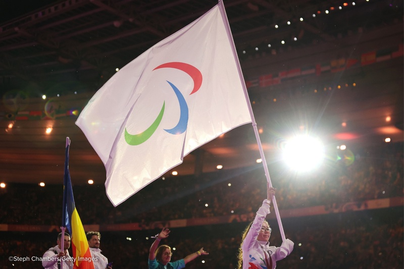 Una joven mujer lleva la bandera del IPC en un estadio iluminado.