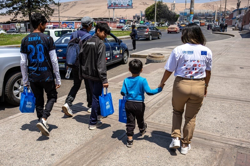 Un hombre, tres niños y una mujer caminan juntos en la calle. La mujer toma de la mano al niño más pequeño de los tres