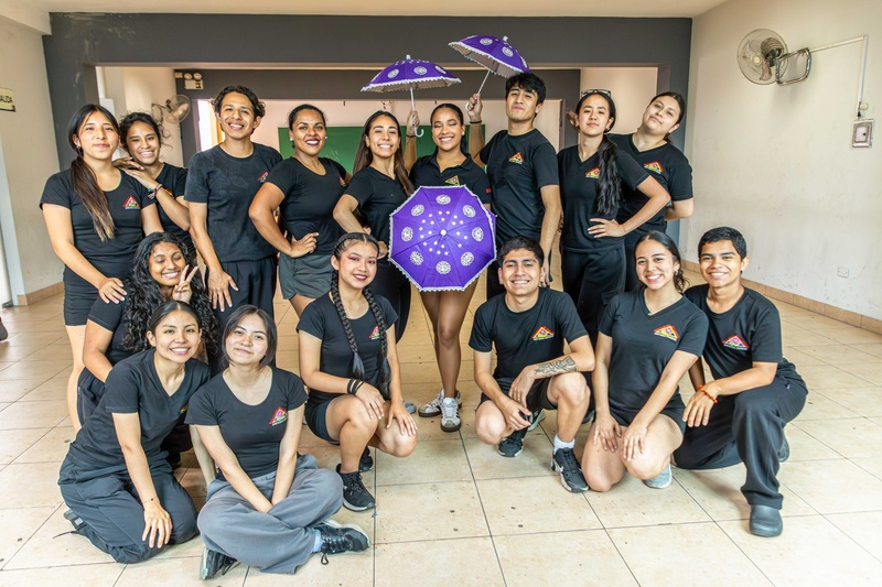 Un grupo de 16 jóvenes posan para la foto con ropa negra en una academia de baile