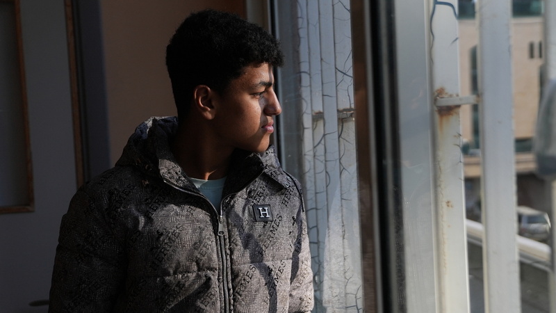 Un joven mira por una ventana.