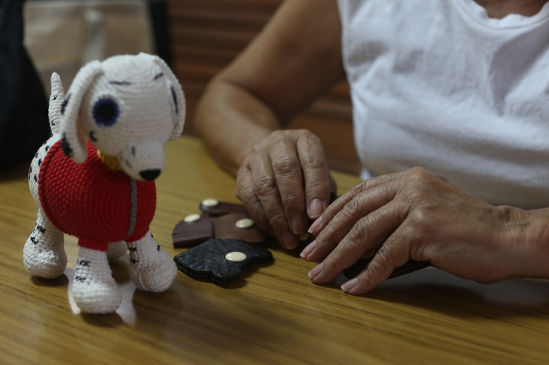 Las manos de una mujer sobre una mesa de madera junto a un perrito tejido