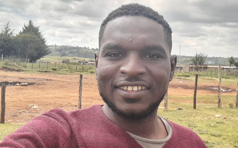 Un hombre sonríe al tomarse una selfie en un entorno rural.