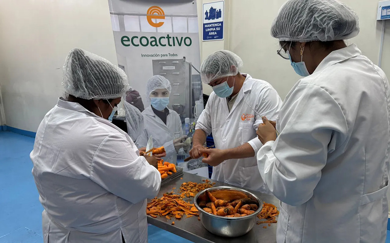 Un grupo de personas con mascarillas y gorros manipulando alimentos en una actividad de ECOACTIVO.
