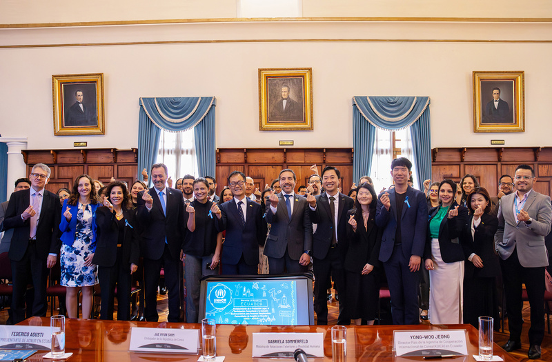 Más de 30 personas posan de pie para la foto mientras hacen una señal de corazón con su mano