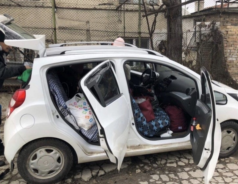 Un pequeño automóvil blanco, con las puertas y el maletero abiertos, está repleto de equipaje