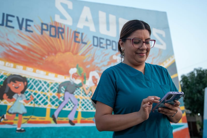 Una mujer con un uniforme de enfermera mirando su teléfono.