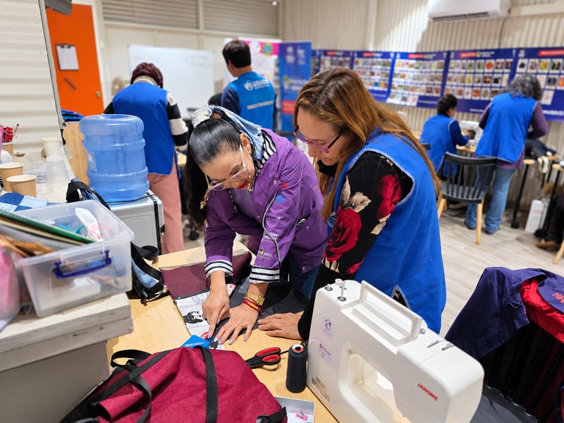 Dos mujeres observan un trozo de tela en un taller de costura