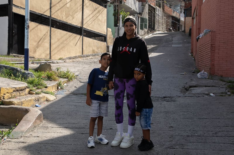 Una mujer posa para una foto en una calle junto a un niño y una niña.