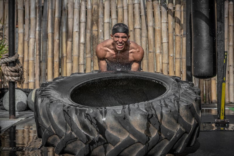 Un boxeador venezolano, que lleva puesta una gorra, se esfuerza por levantar un neumático enorme