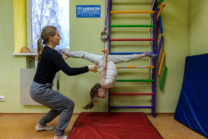 Un niña hace un split de cabeza con la ayuda de una instructora en Ucrania