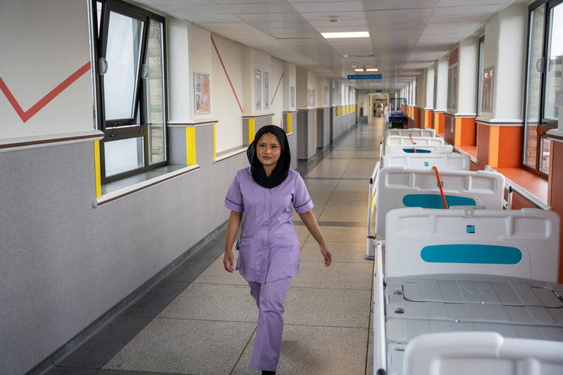 Una mujer en uniforme de enfermera camina en el pasillo de un hospital.