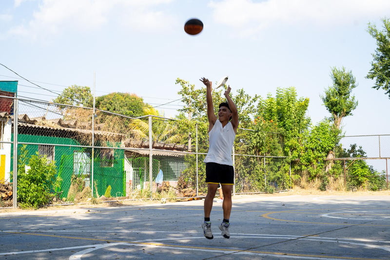 Un joven jugando baloncesto en una cancha deportiva.
