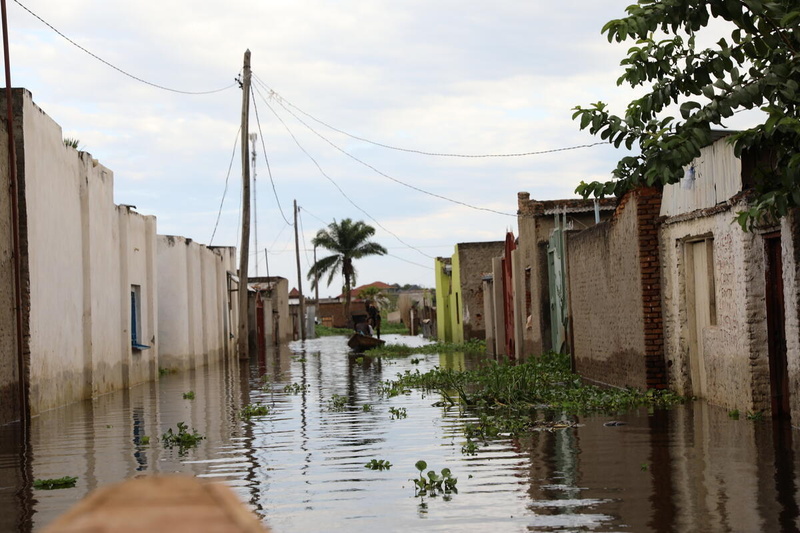 Un hombre navega en una embarcación de madera por una calle residencial inundada