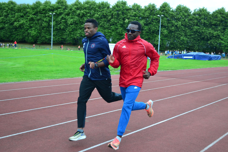 Dos atletas con un lazo de sujeción corren uno junto al otro en una pista de atletismo