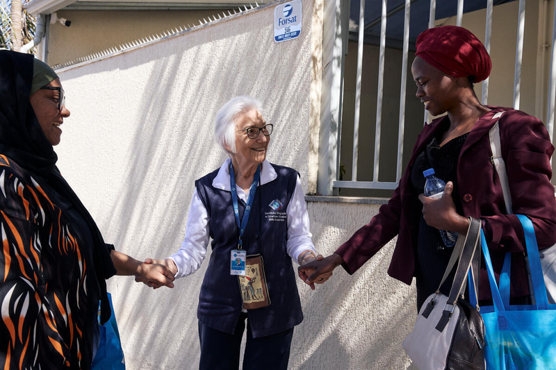 Tres mujeres sonrientes se dan la mano en el exterior de un edificio